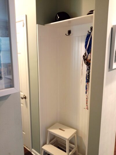 A small alcove with beadboard, coat hooks and shelf